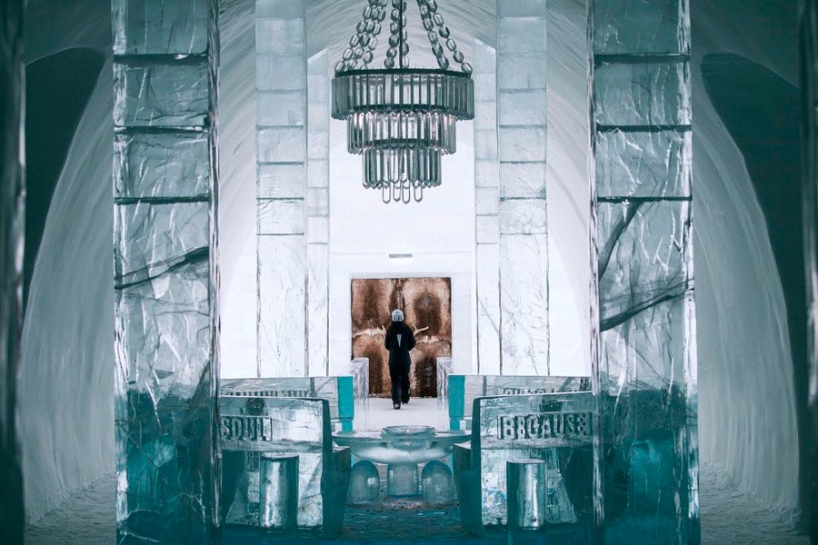 A large hall made entirely of ice and snow, with ice benches and an ice chandelier.