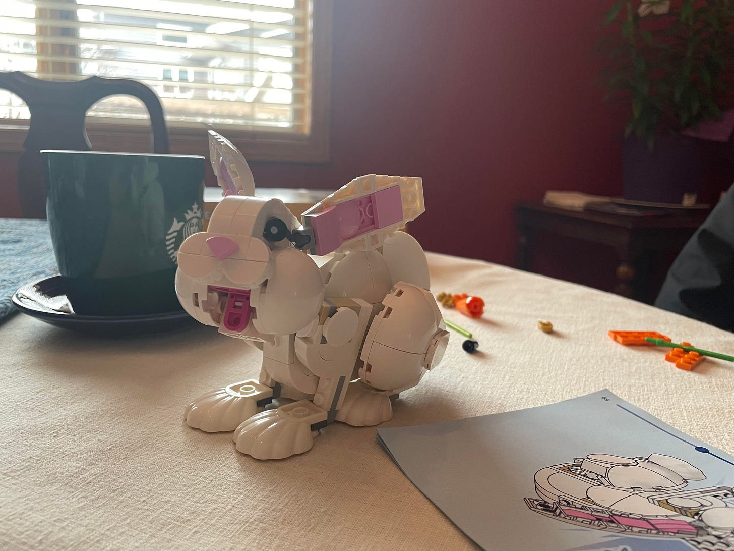 A completed LEGO rabbit sits on a table near a cup of coffee