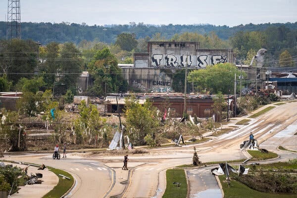 A muddy crossroads with damaged buildings in the background.