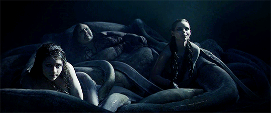 GIF of Syrens and sea witch from the 2017 film King Arthur: Legend of the Sword. Syrens are slowly crawling over the writhing tentacles of the sea witch. The aesthetic is haunting and sinister.