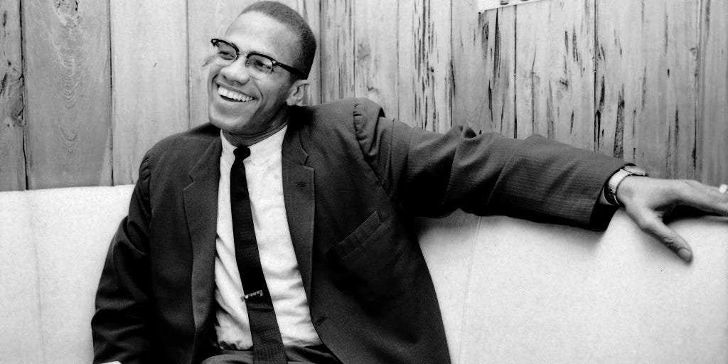 a black and white image of malcolm x smiling
