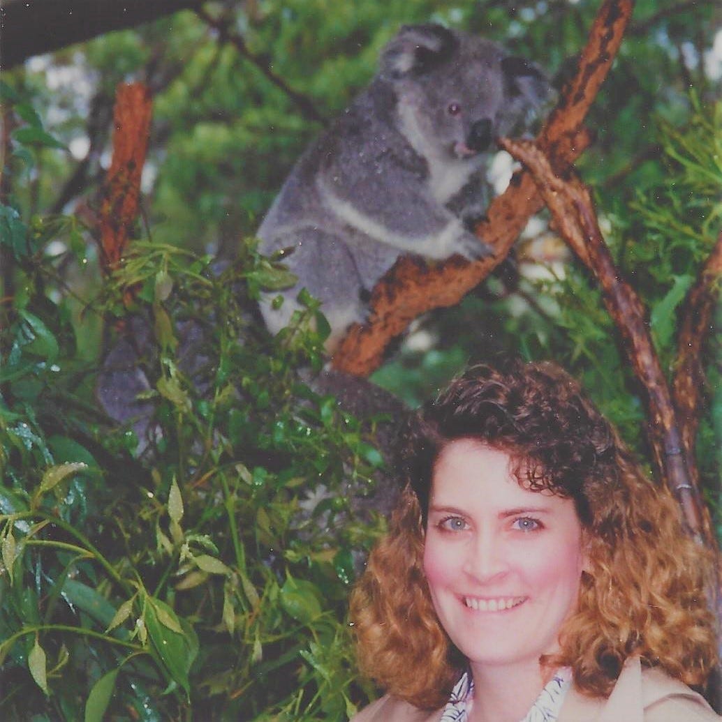 Young woman with Big 80s hair poses with a koala bear perched in the background