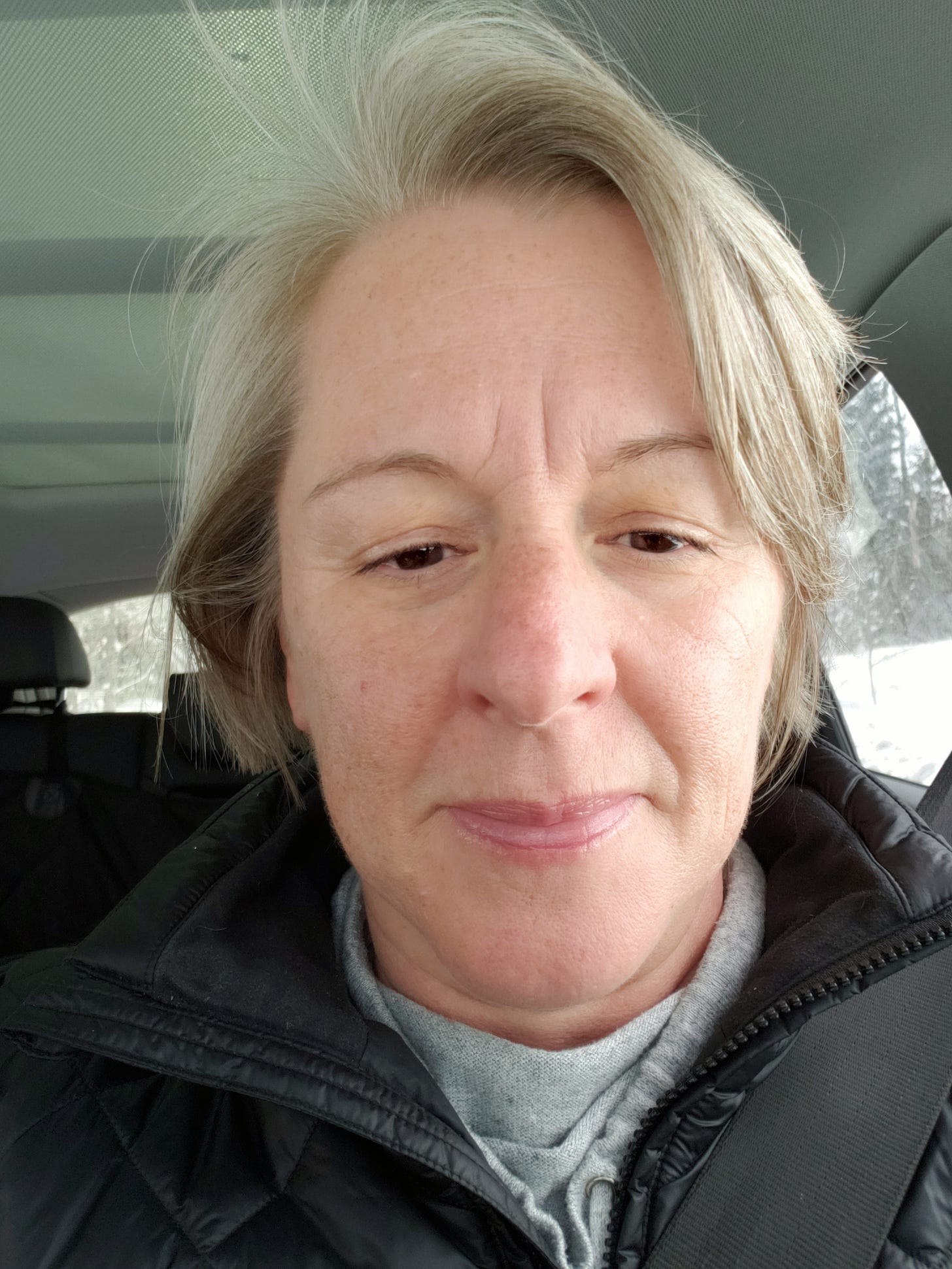 A middle-aged woman with short grey hair wears no makeup and has deep wrinkles between her eyes