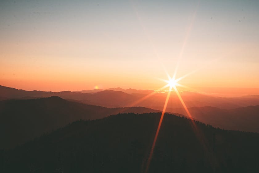 Sun shining as it nears the horizon over the mountainous hills