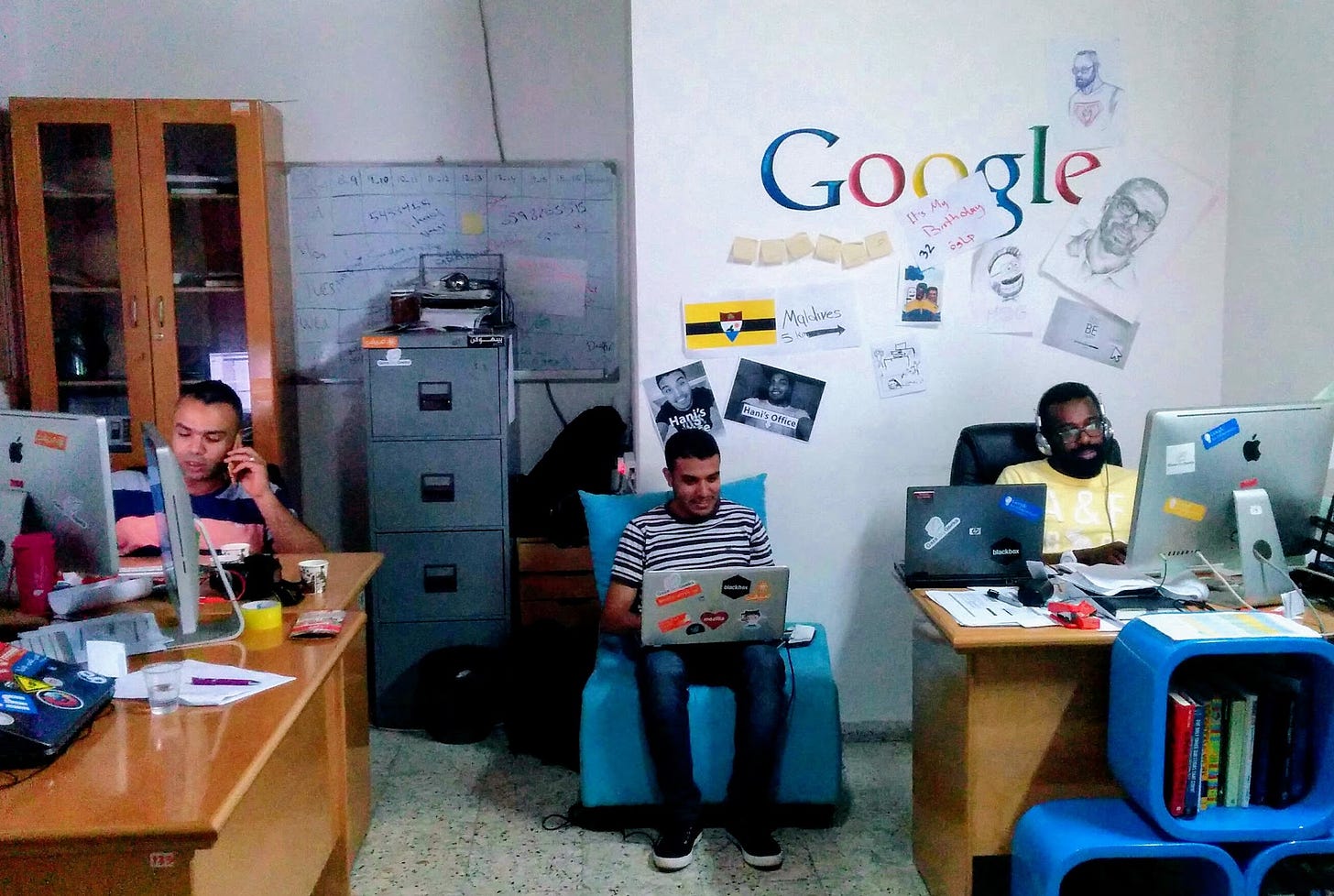 Three men working on computers in a colorful office