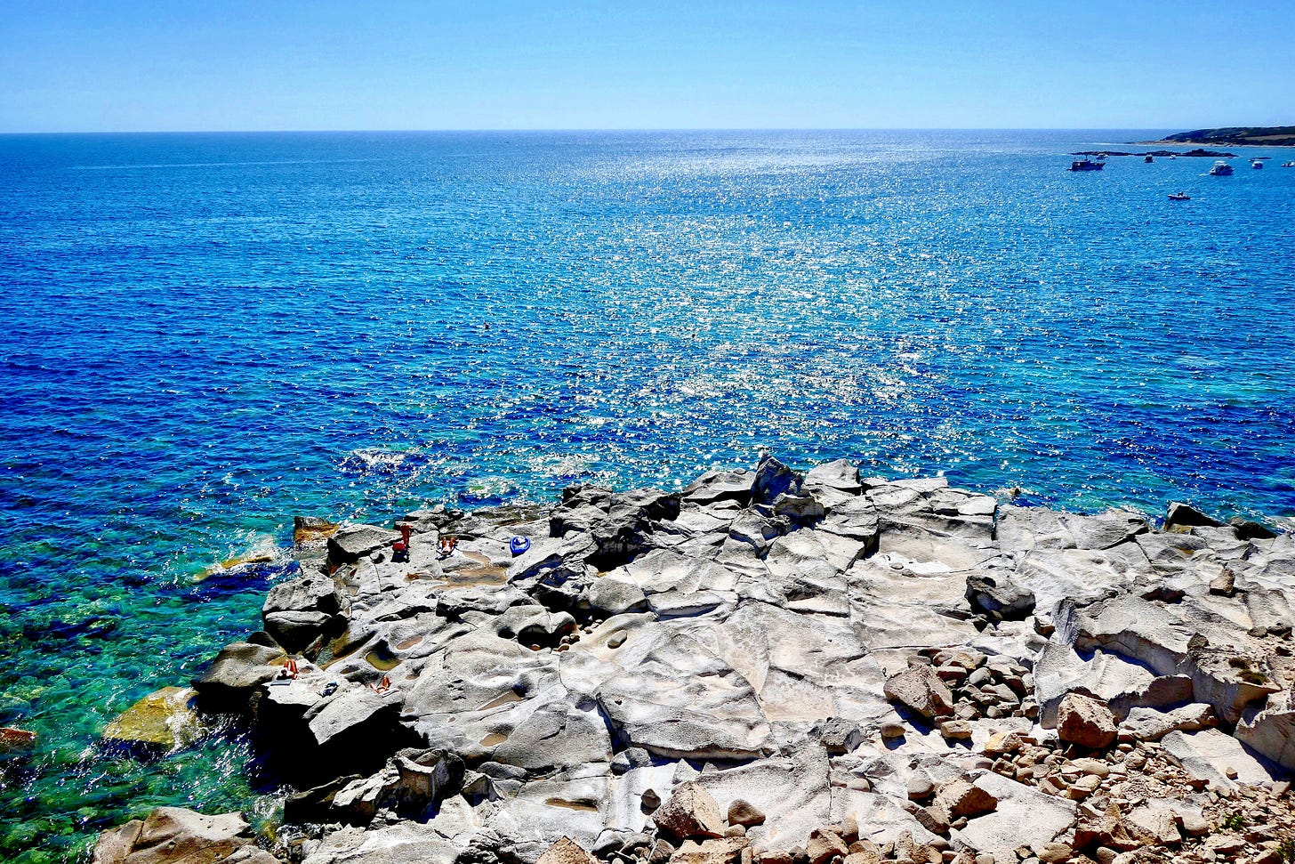 propaggie rocciosa dell'isola di Carloforte che si protente nel mare azzurro, con l'orizzonte sullo sfondo