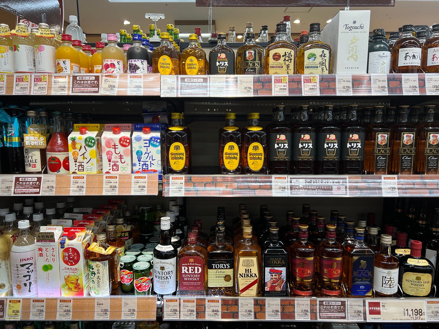 A shelf of whiskey bottles at a Japanese supermarket.