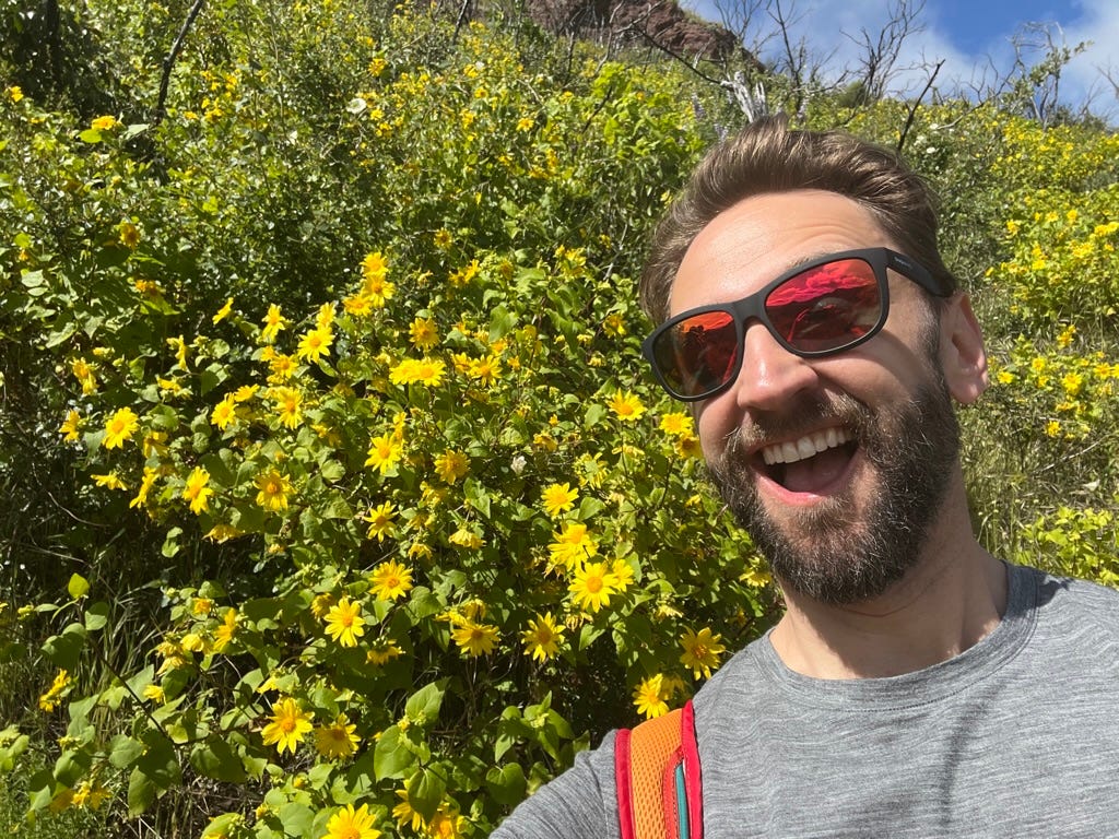 A person taking a selfie in front of yellow flowers

Description automatically generated