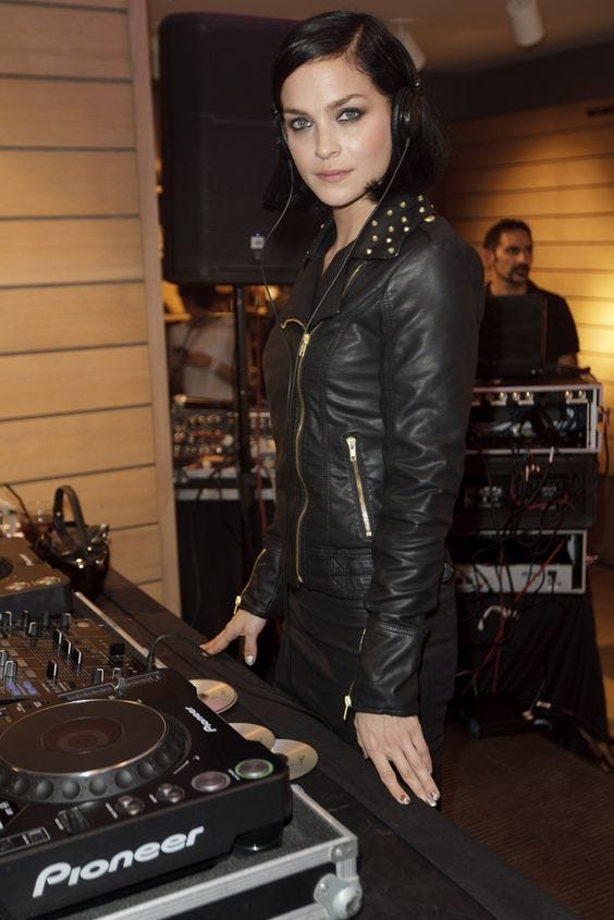 This may contain: a woman standing in front of a dj's turntable