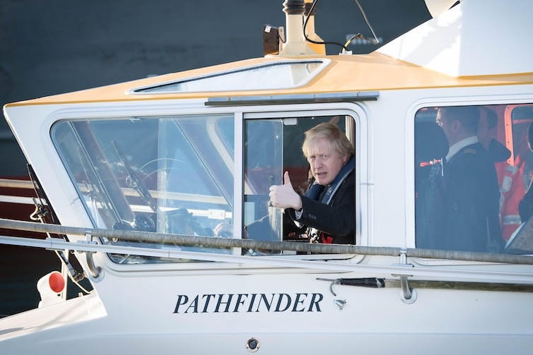 Boris Johnson in the cabin of a ship called Pathfinder, giving a thumbs up from the window.