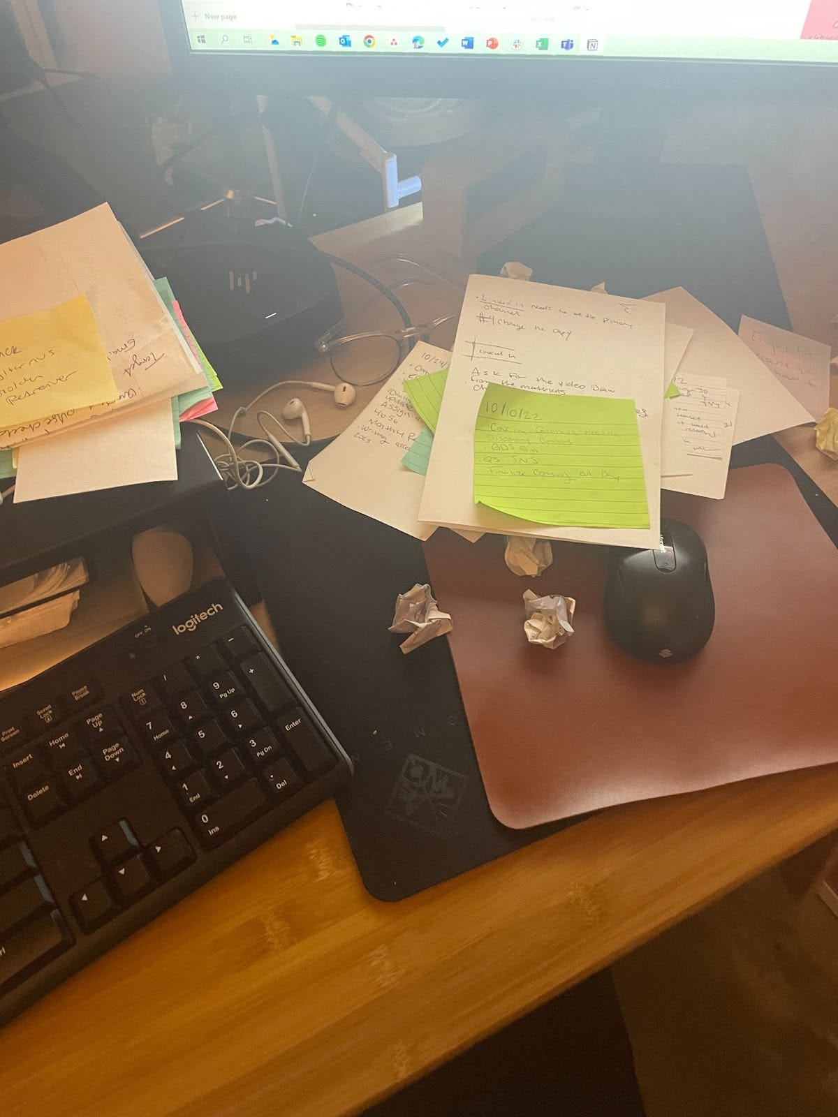 A messy desk, covered in loose papers and sticky notes