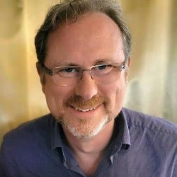 A picture of a white man in a purple shirt and glasses