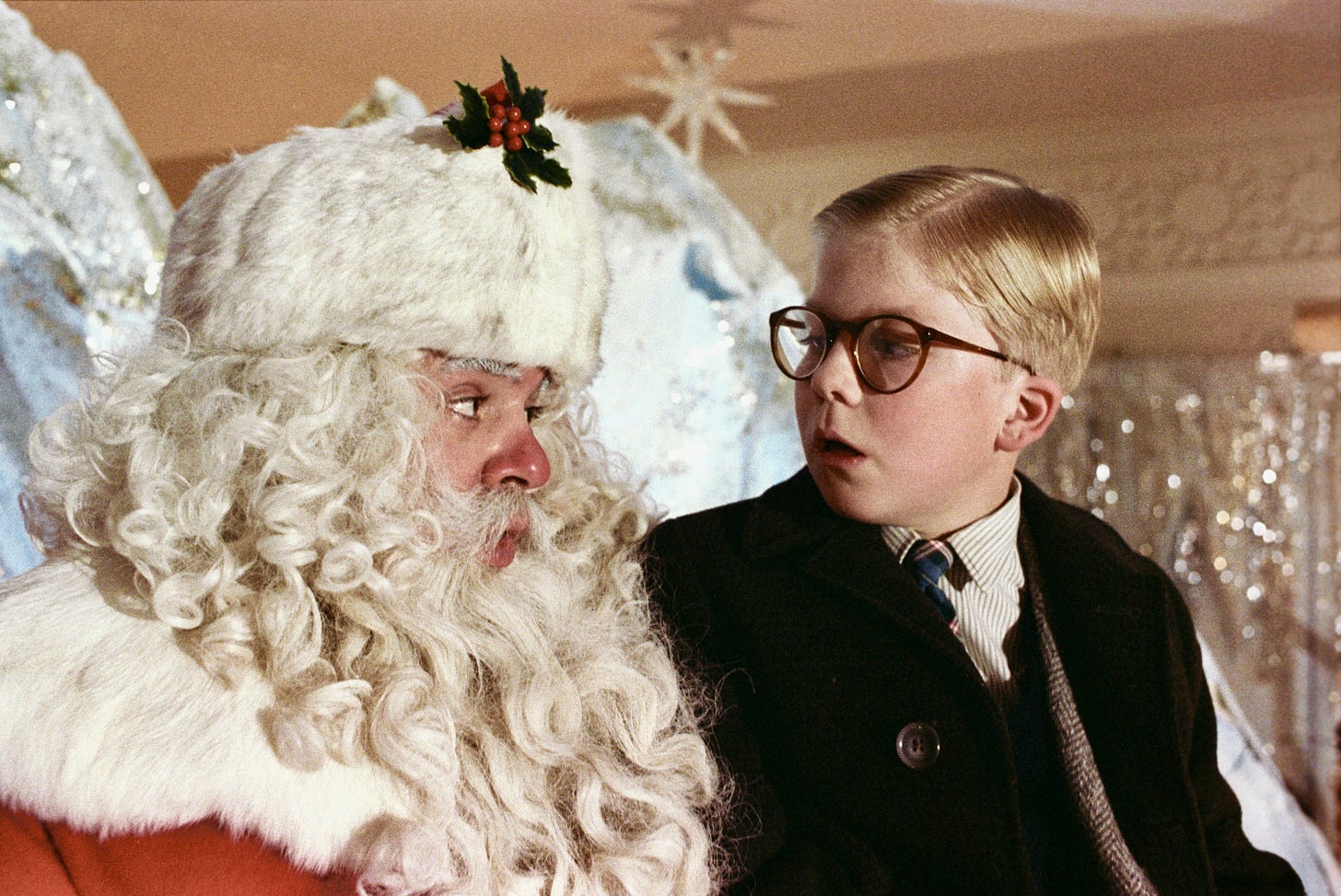 A bespectacled boy sits on the lap of a department-store Santa