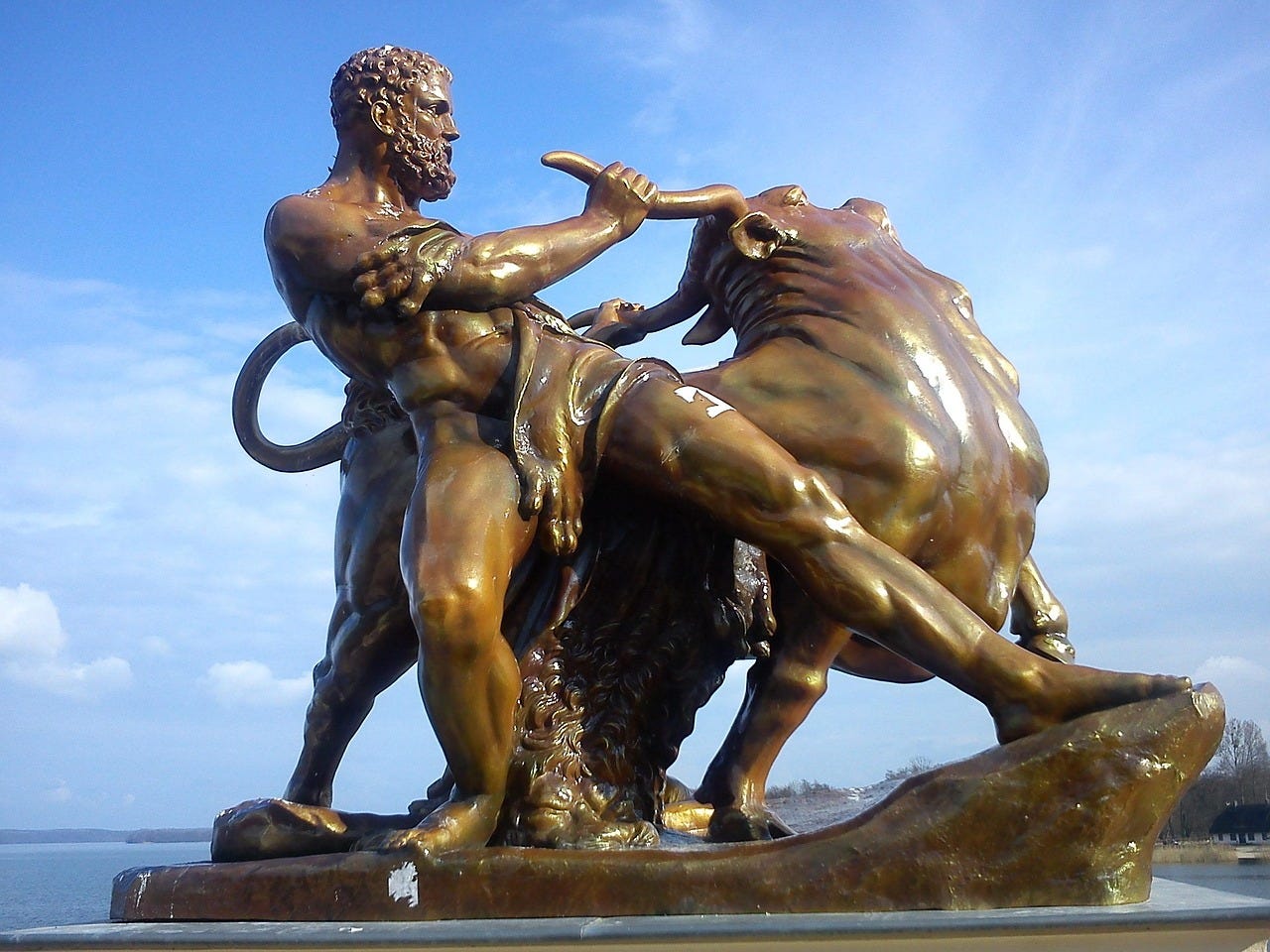 An ancient Greek hero wrestles a bull. Bronze statue.