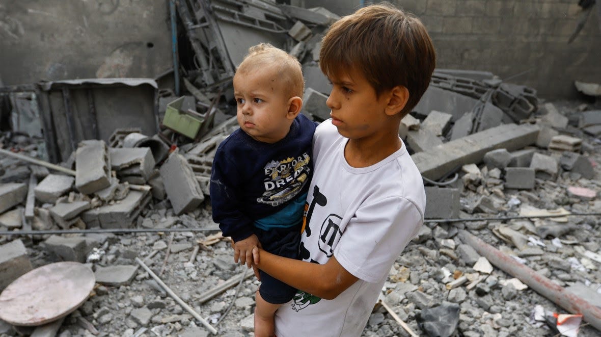 A child hold a toddler amid rubbles in Gaza.