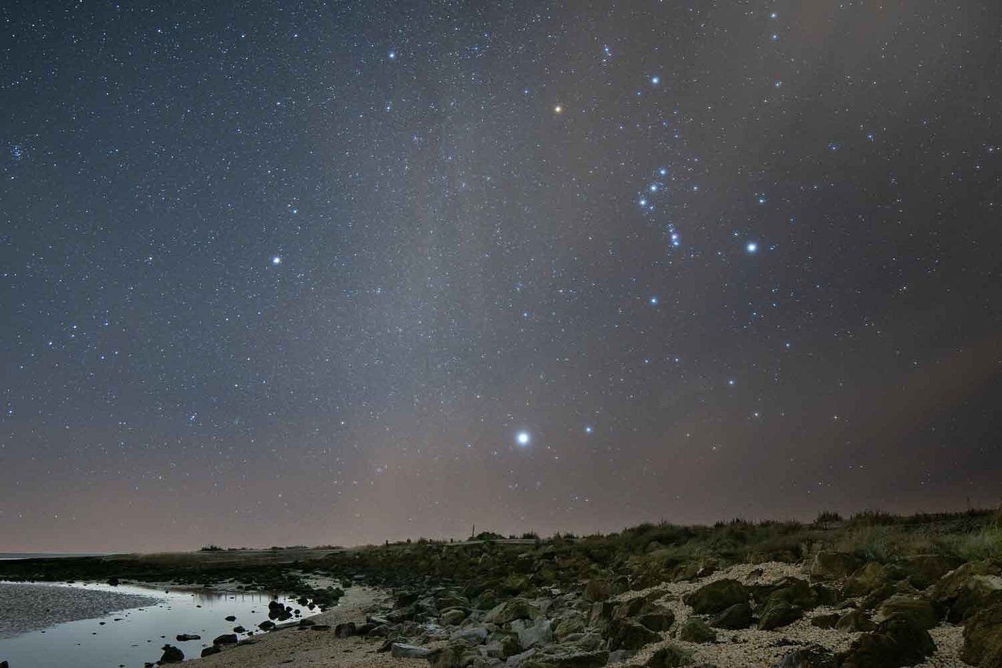 Orion high in the sky over a beach