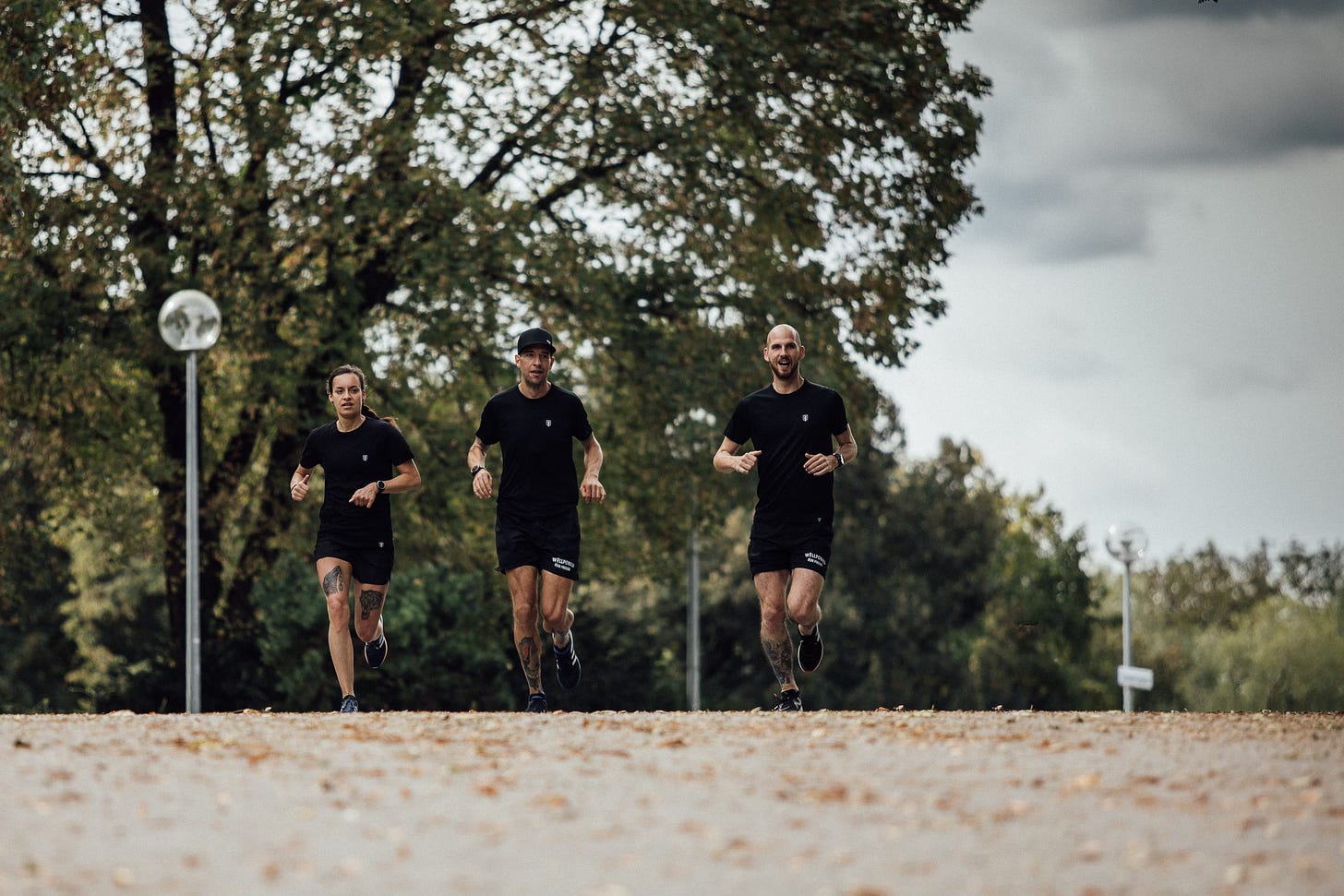 Three runners in black clothing on a training run in the olympic park munich