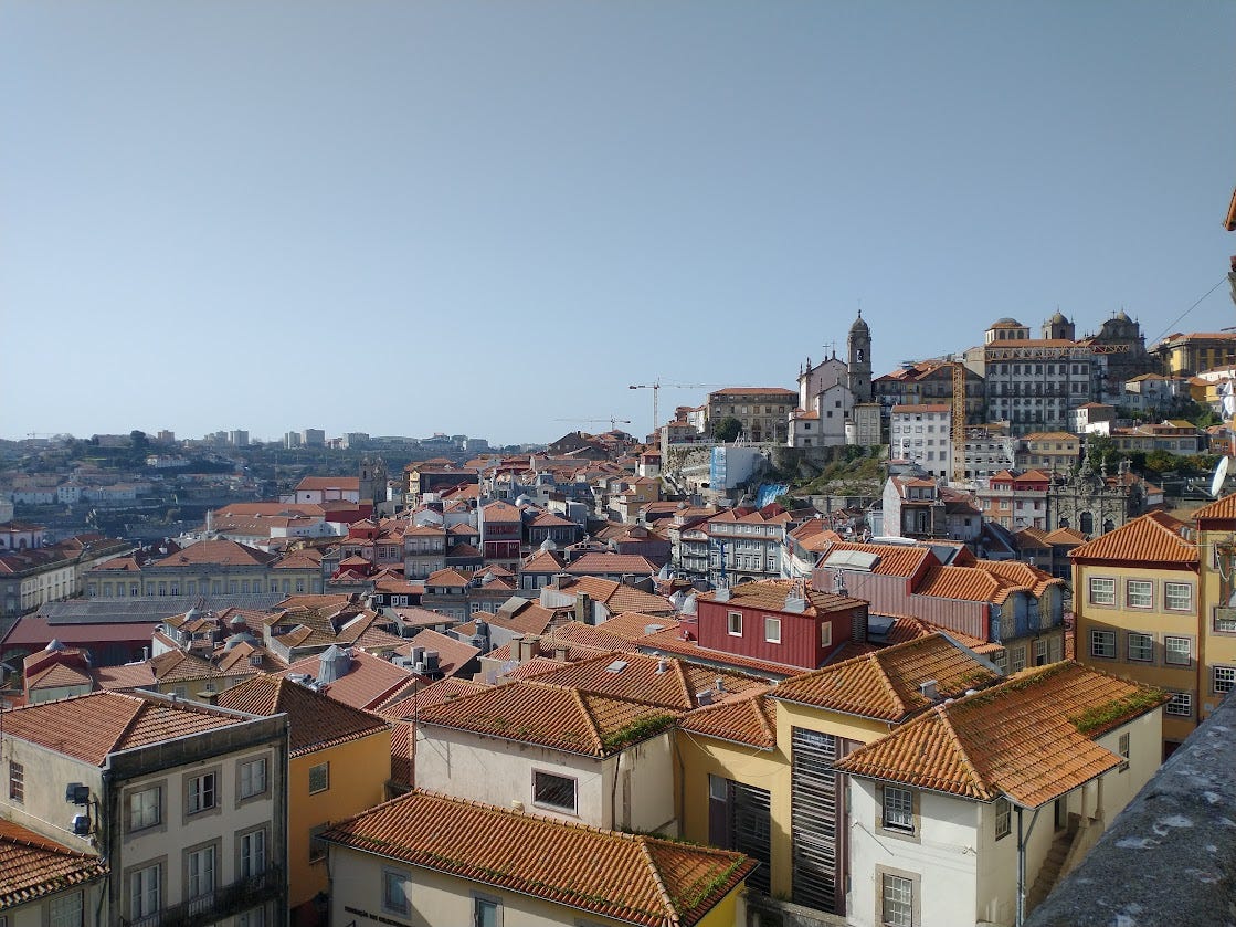 Looking out over the red-tiled rooftops of the oldest part of Porto. The buildings are built closely together all the way down to the Douro River on the left.