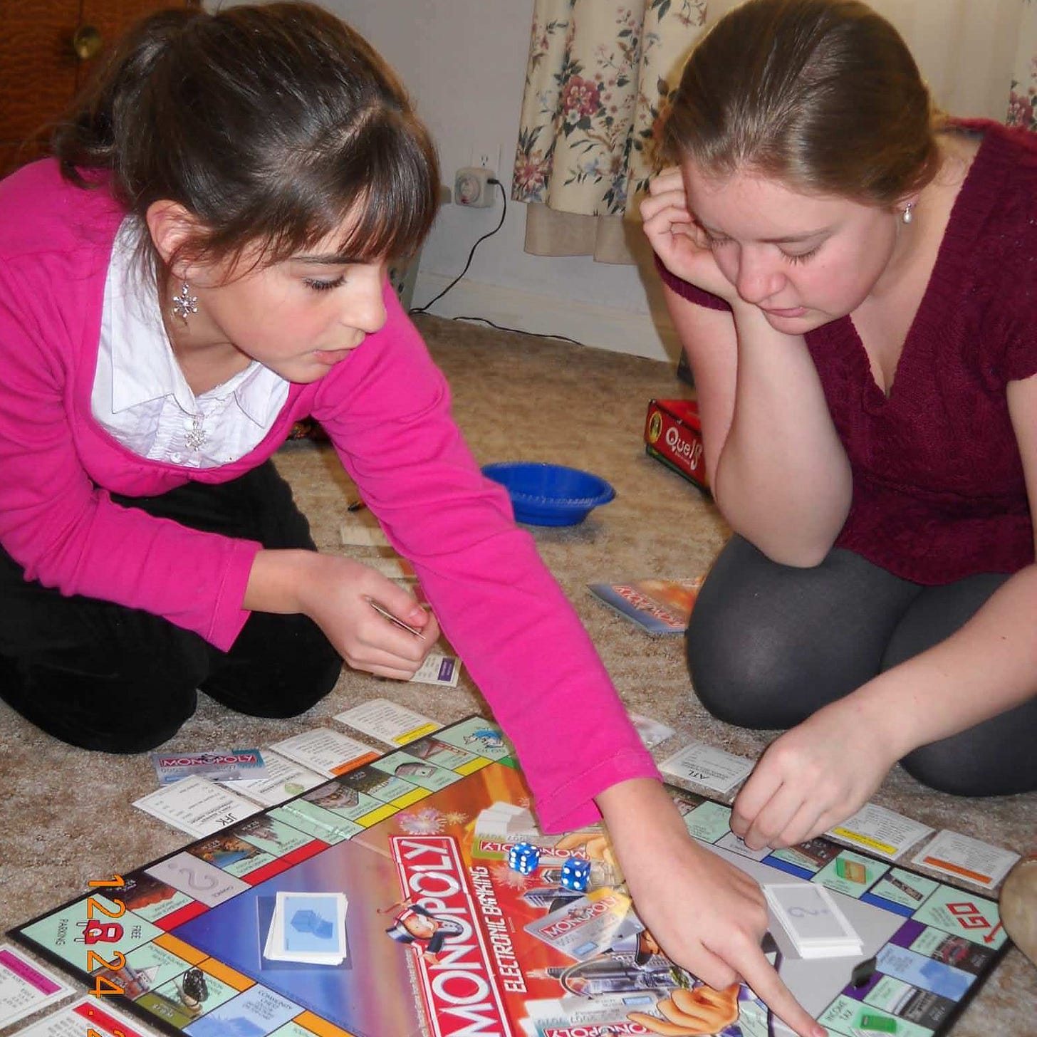 Two teen girls sitting on the floor playing a board game