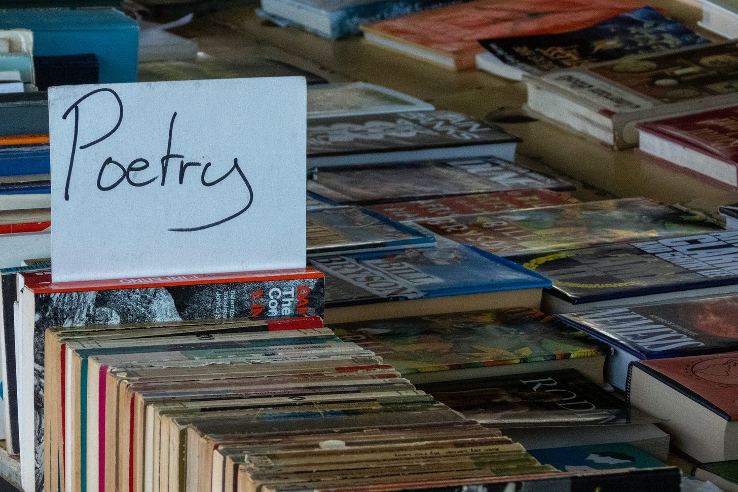 books stacked up for sale with sign saying poetry on top