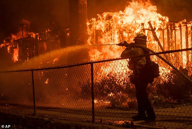A firefighter sprays water on a home burning in the Eaton Fire in Altadena, California on Wednesday, January 8, 2025