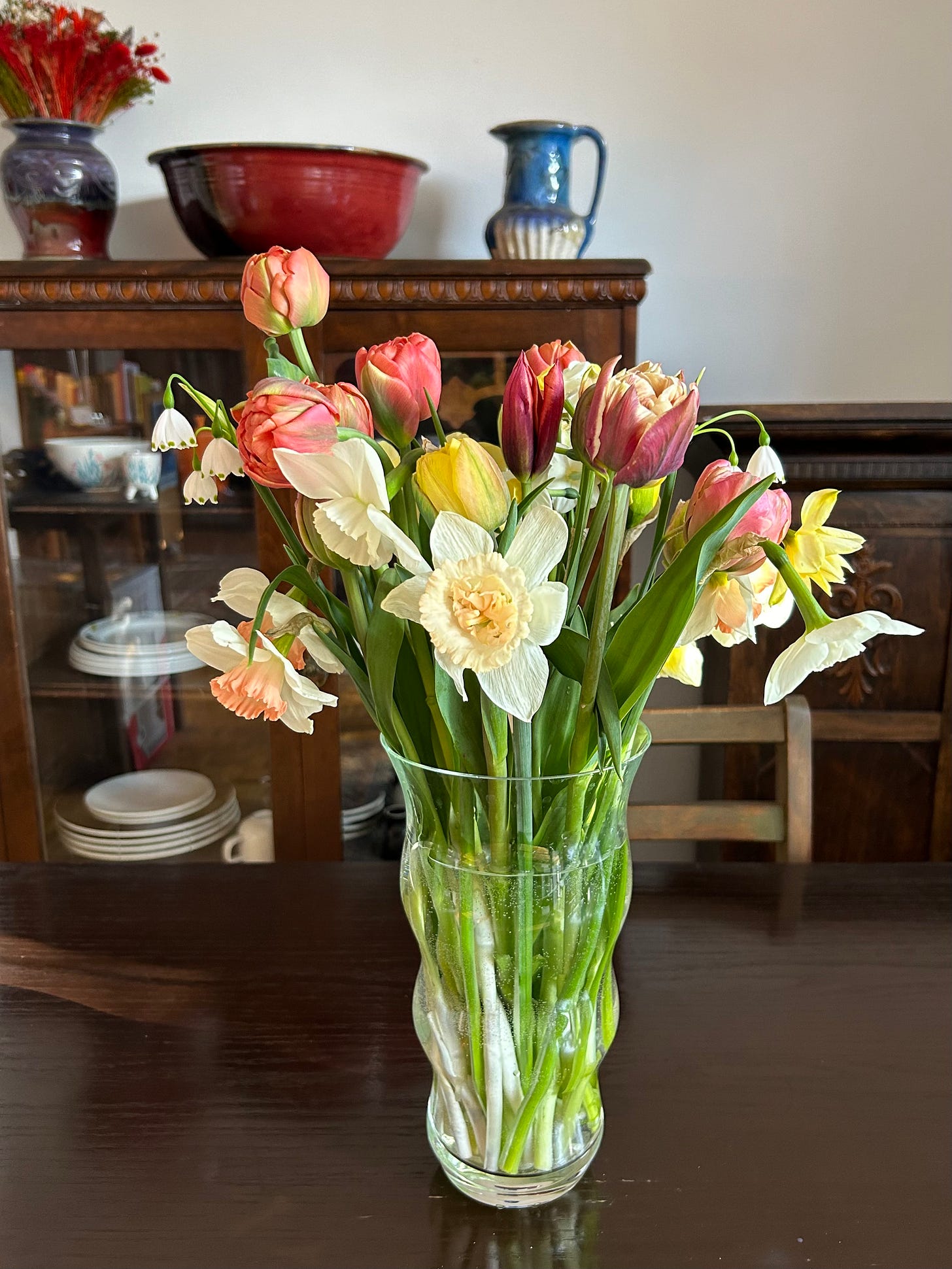 Glass vase of tulips on wood table.