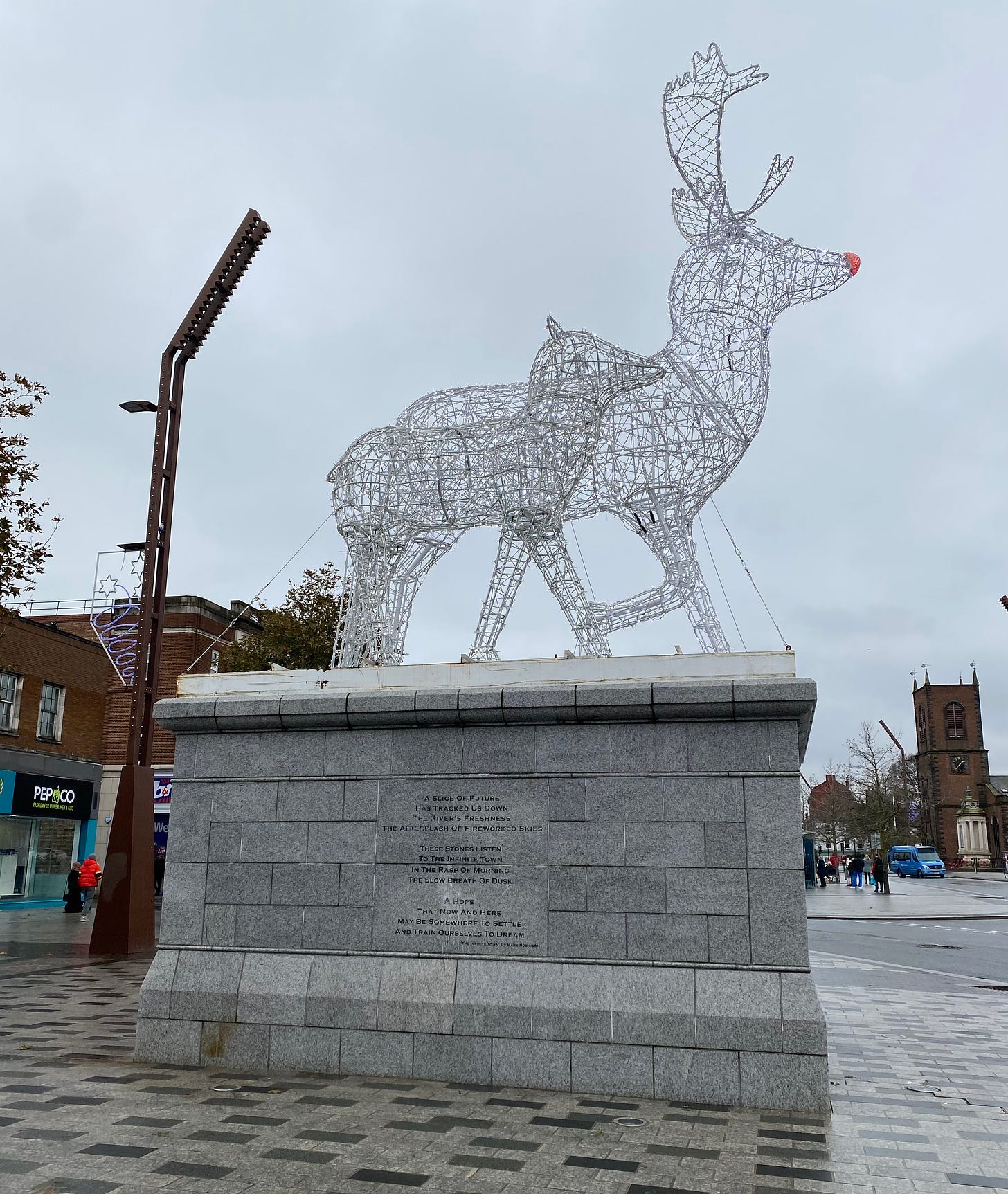 Wire reindeer on a plinth bearing my poem The Infinite Town