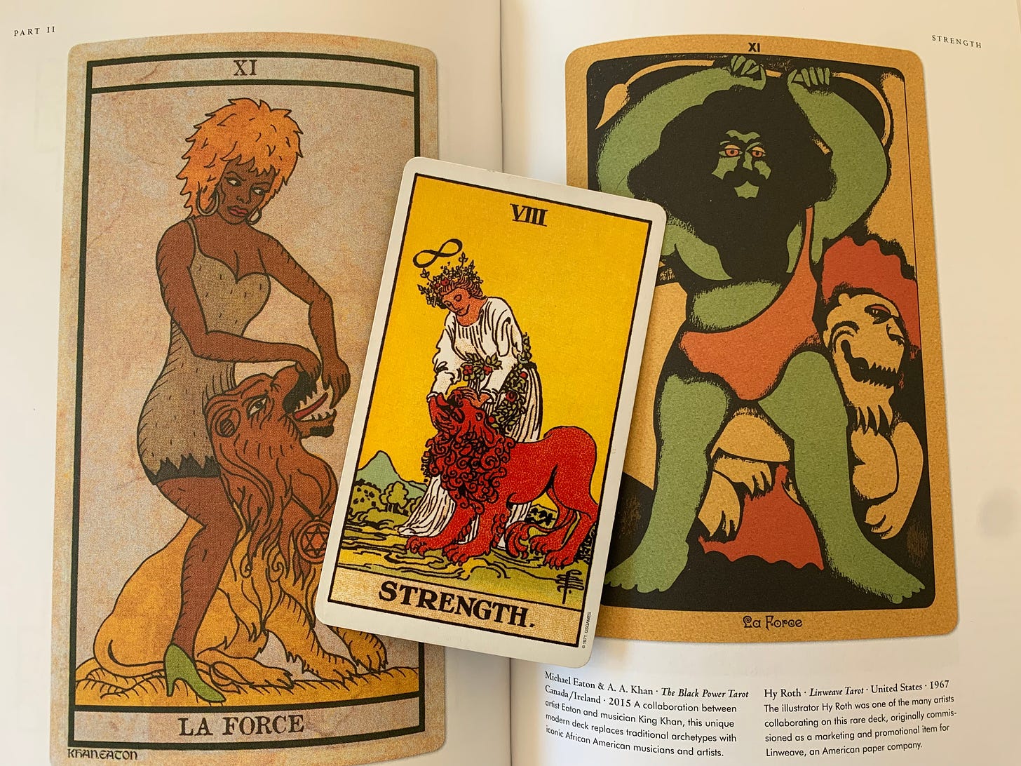A tarot card, Strength, is laid over the open pages of a coffee table book, also featuring illustrations of the card.