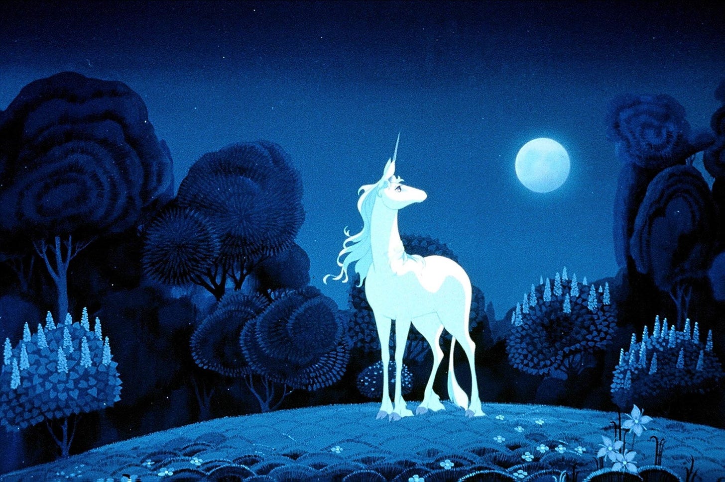 Una scena del film animato L'ultimo unicorno. L'unicorno, bianca, si staglia contro uno sfondo blu scuro che rappresenta una foresta