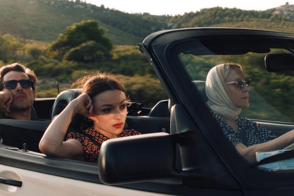 Movie still from Bonjour Tristesse. Two women and a man drive in a car in the summery countryside