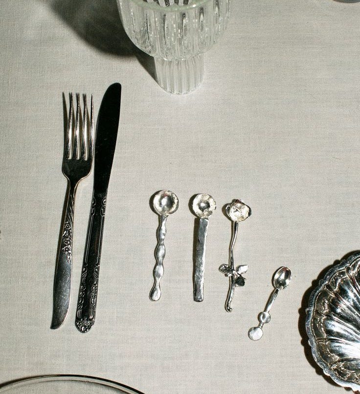 This may contain: the table is set with silver utensils and glassware, including spoons