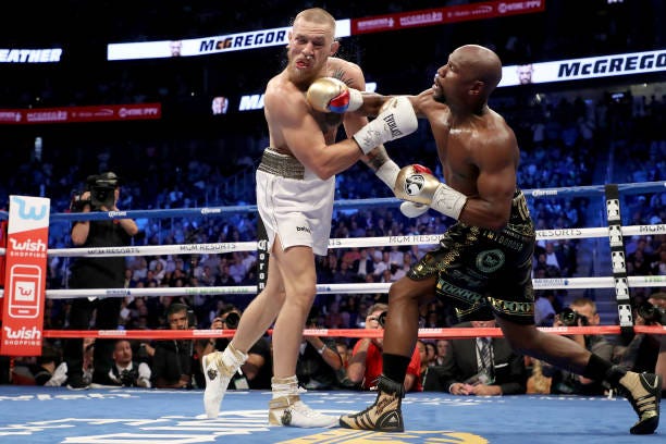 Floyd Mayweather Jr. Throws a punch at Conor McGregor during their super welterweight boxing match on August 26, 2017 at T-Mobile Arena in Las Vegas,...