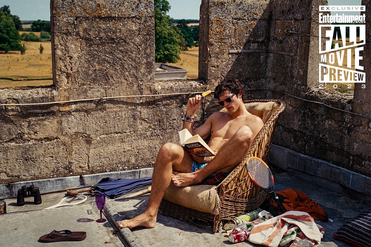 Jacob Elordi in his swim trunks lounging around in a chair reading Harry Potter.