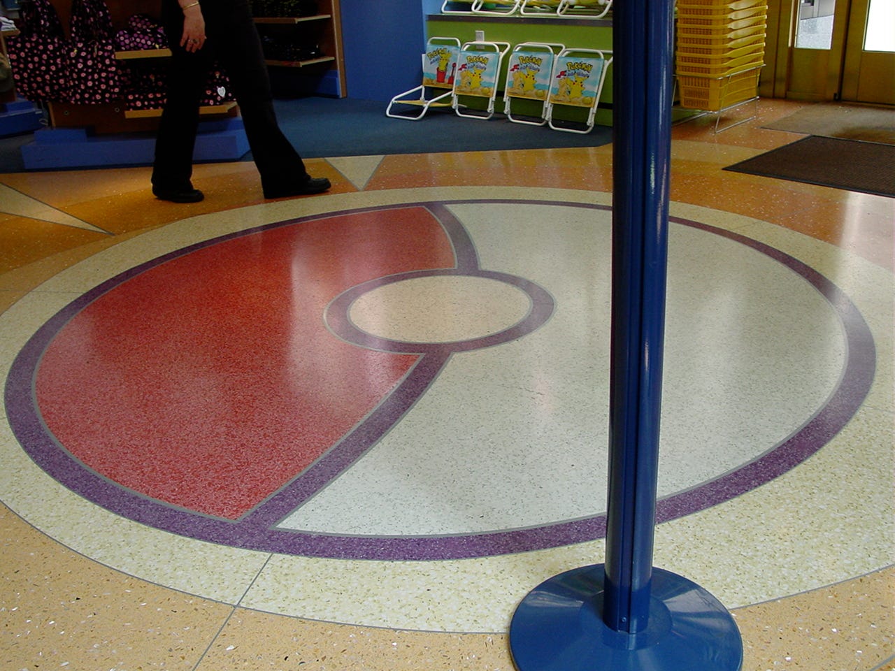 A huge Poké Ball pattern was present on the lower floor of the store. This photograph also shows Pokémon deckchairs and bright yellow shopping baskets by the entrance