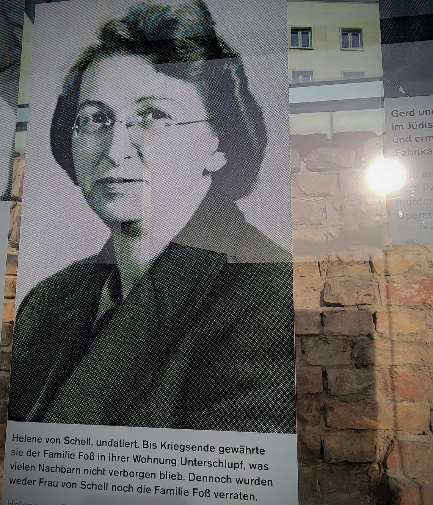 A photograph of a photograph that is displayed in a history exhibit. The photo in the image is a portrait of a middle-aged Caucasian woman with glasses, looking calmly into the camera.