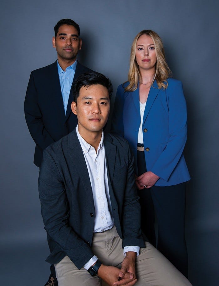 Sudharsan Dwaraknath and Laura Stoy stand behind Andrew Wang, who is seated. All are in professional attire and looking at the camera.