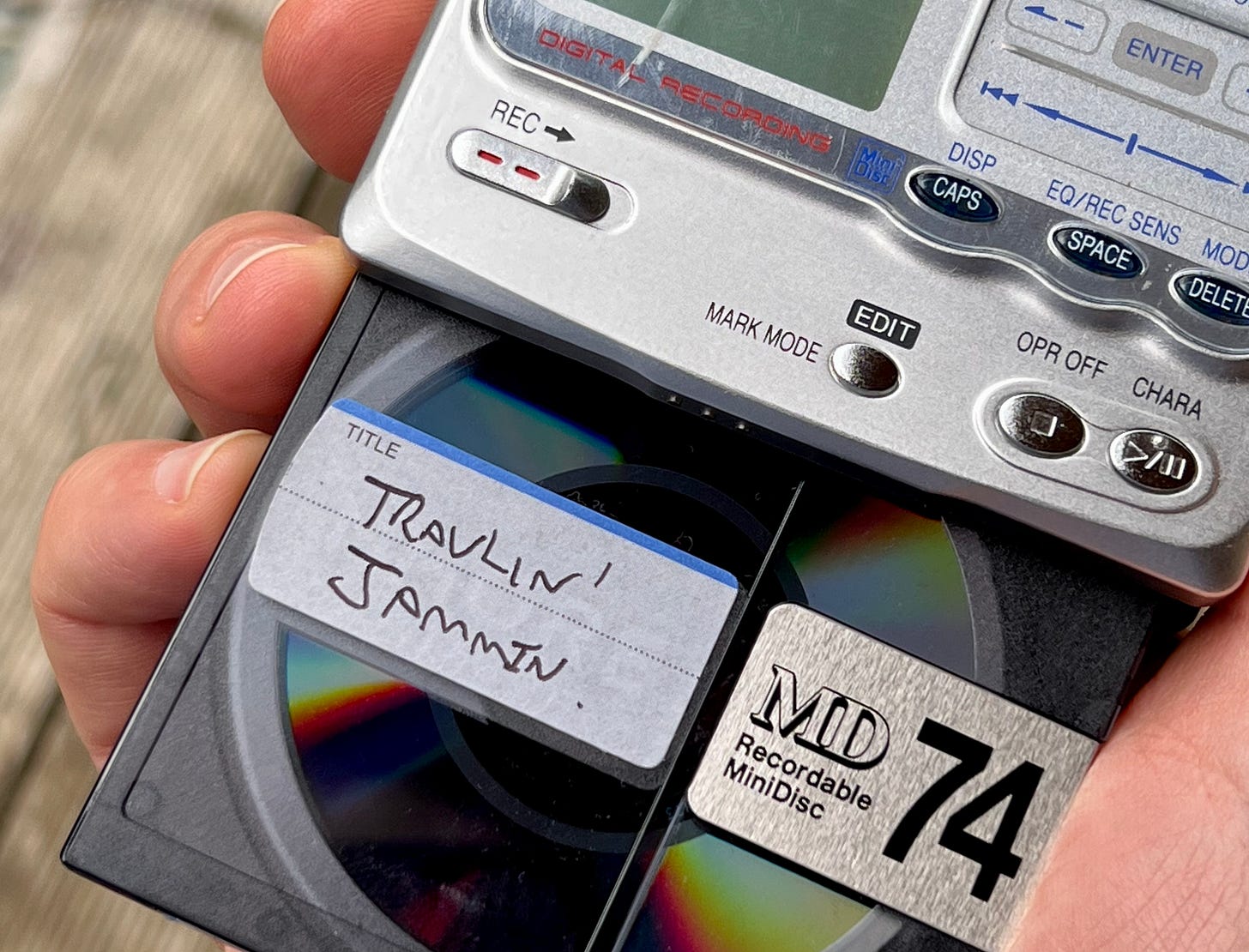 An Image of a mini displayer with her MiniDisc hanging out of it saying travellin' jammin