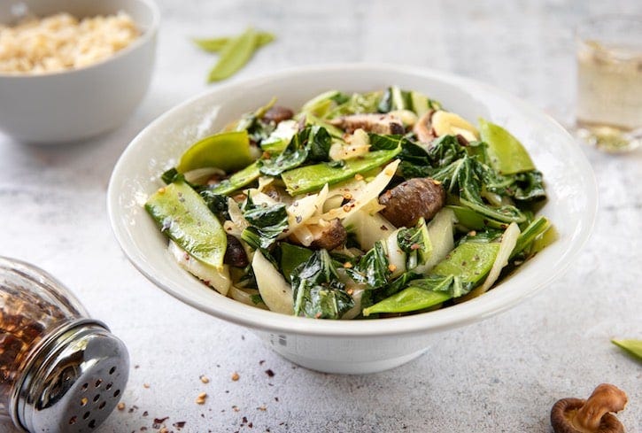 Stir-fried bok choy and shiitake mushrooms with snow peas plated