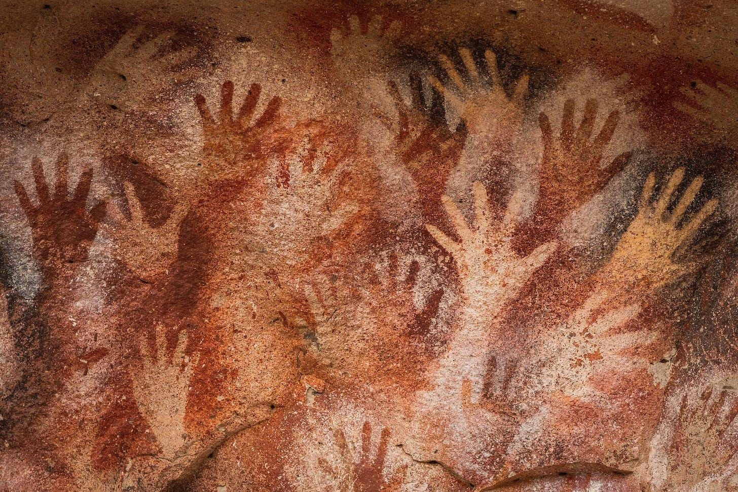 A close-up of a cave painting with Cueva de las Manos in the background

Description automatically generated