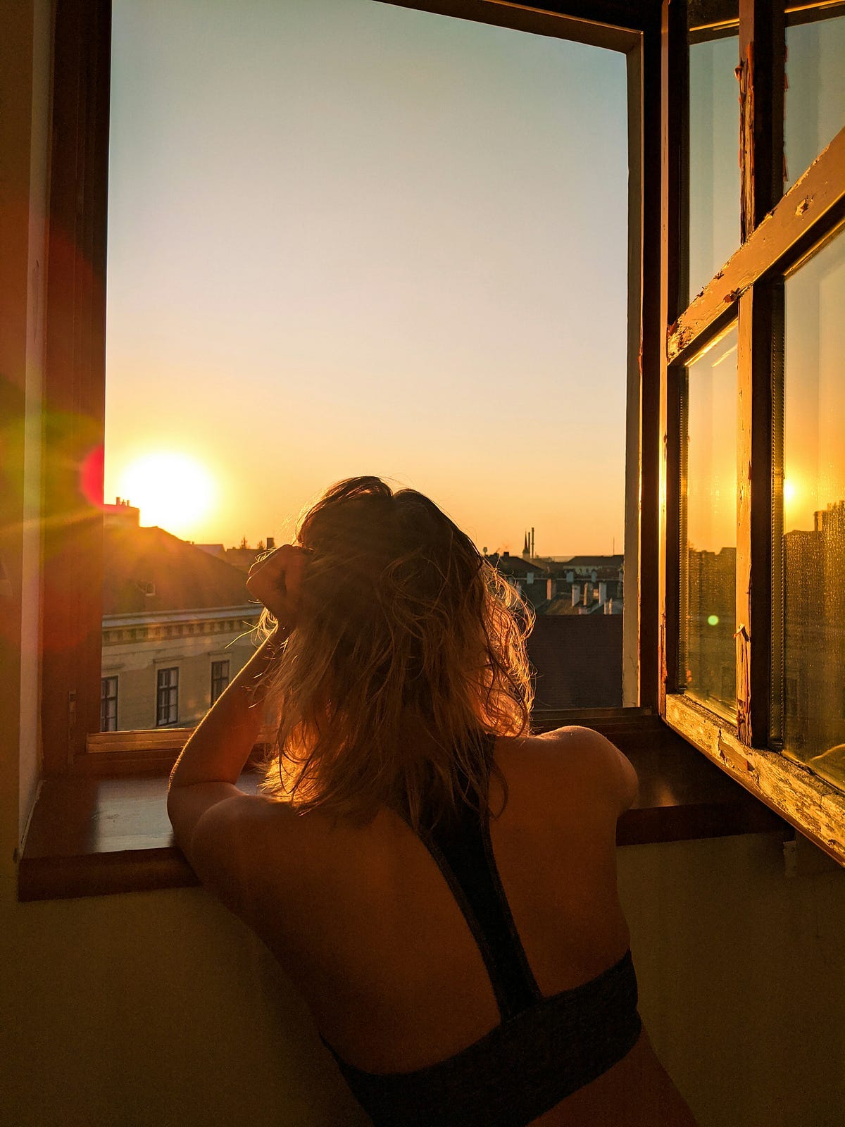 Woman looking out of a window at a sunrise Woman looking out of a window at a sunrise