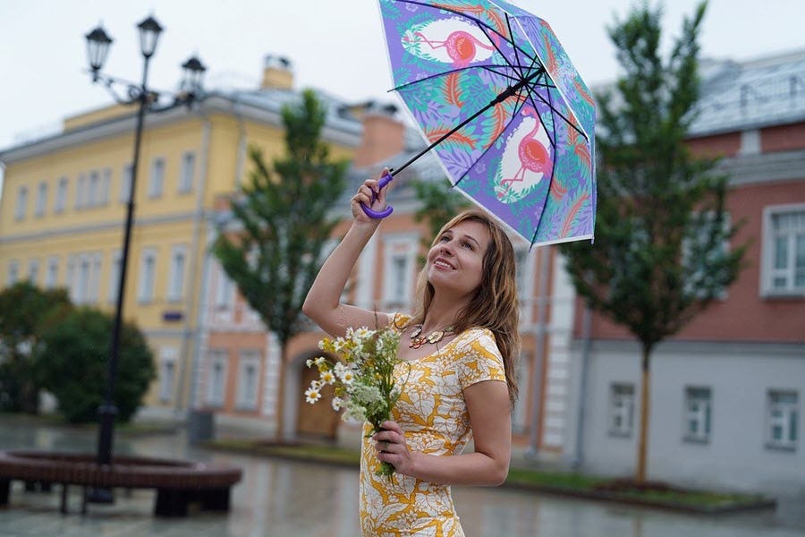 woman with umbrella and flowers dancing in the rain