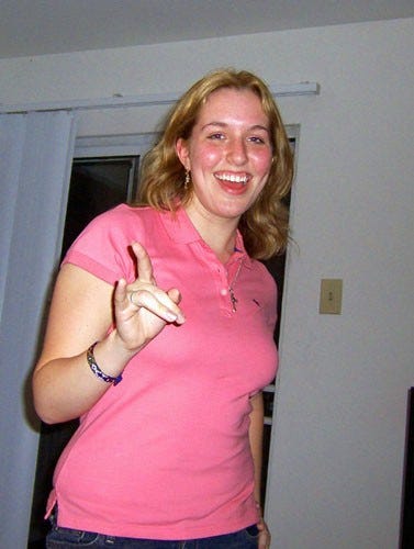 Photo of a slender blonde 20 year old woman with blonde hair and a big smile, wearing a pink polo shirt and jeans