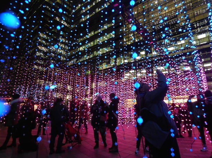 Canary Wharf Winter Lights 2025: people silhouetted among illuminated hanging threads