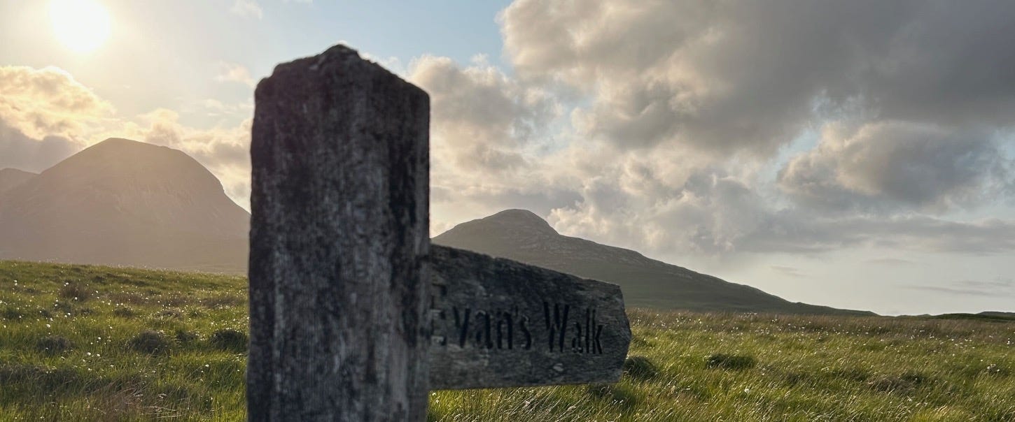 Wooden signpost against mountains and sunset sky