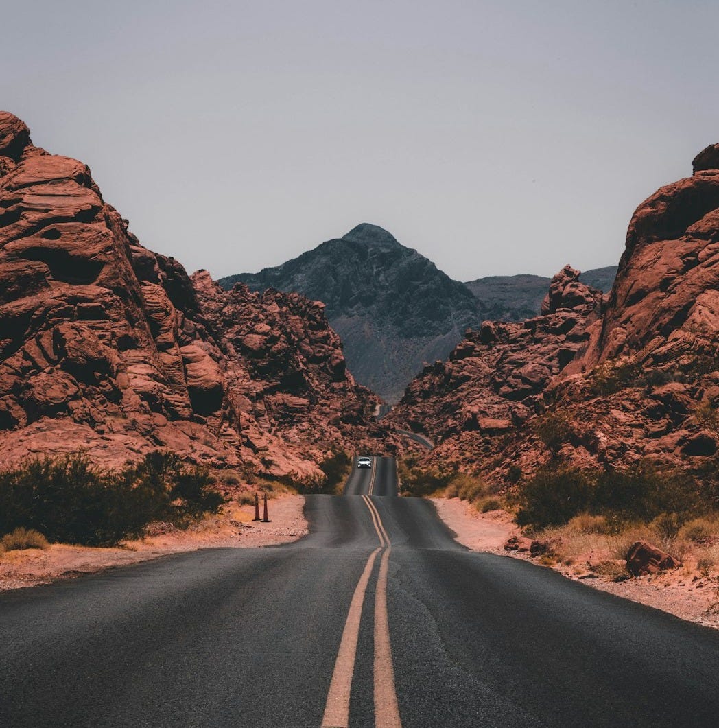 black concrete road surrounded by brown rocks black concrete road surrounded by brown rocks