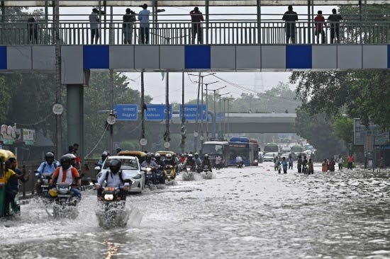People wade through a flooded street in New Delhi.