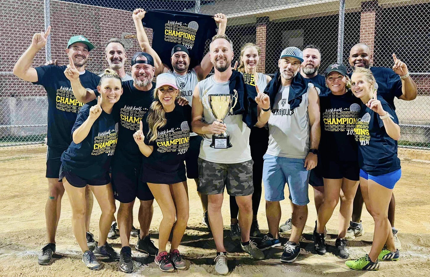 A group of men and women holding up their index fingers and a trophy