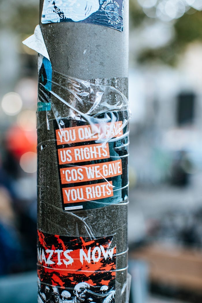 A sticker attached to a light pole that reads: “You only gave us rights ‘cos we gave you riots.” A sticker attached to a light pole that reads: “You only gave us rights ‘cos we gave you riots.”