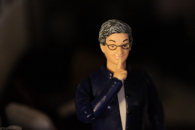 Foreboding close-up image of the Nancy Pearl librarian action figure shushing against a dark background.