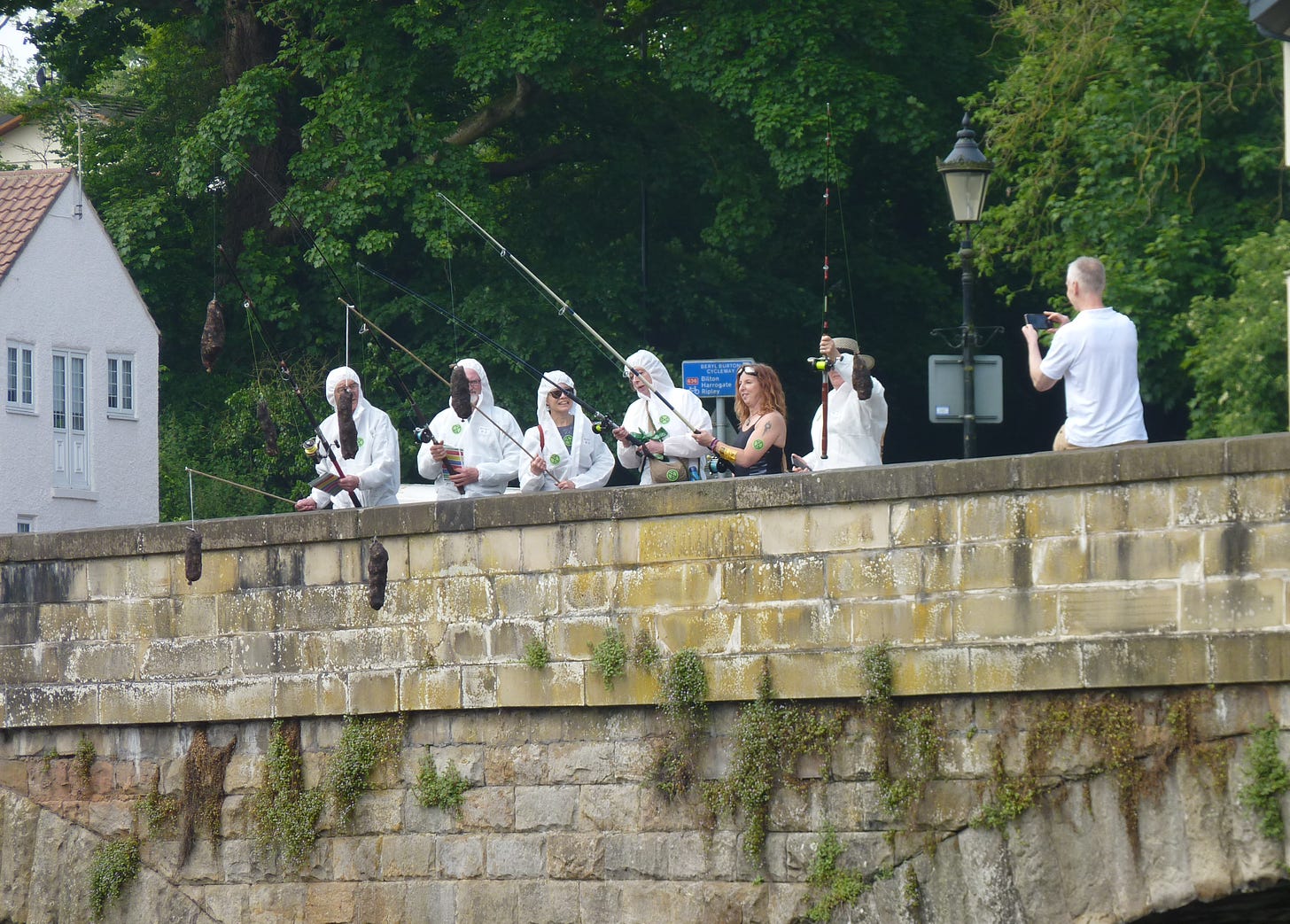 People with fishing rods stood on a bridge over a river fishing for poo as part of a protest